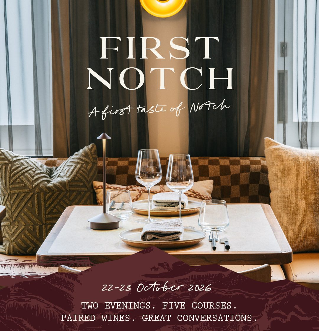 A warmly lit restaurant booth with a set table and wine glasses; poster text announces First Notch, October 22–23, 2026.