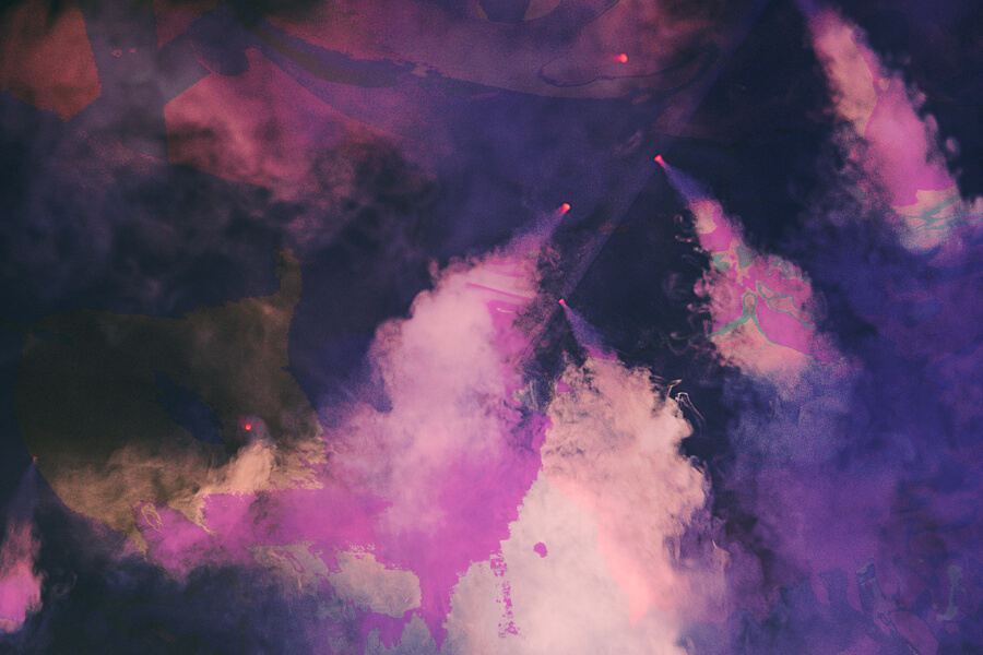 Purple and pink smoke fills the scene with bright beams of light emerging, creating a dramatic, colorful atmosphere.