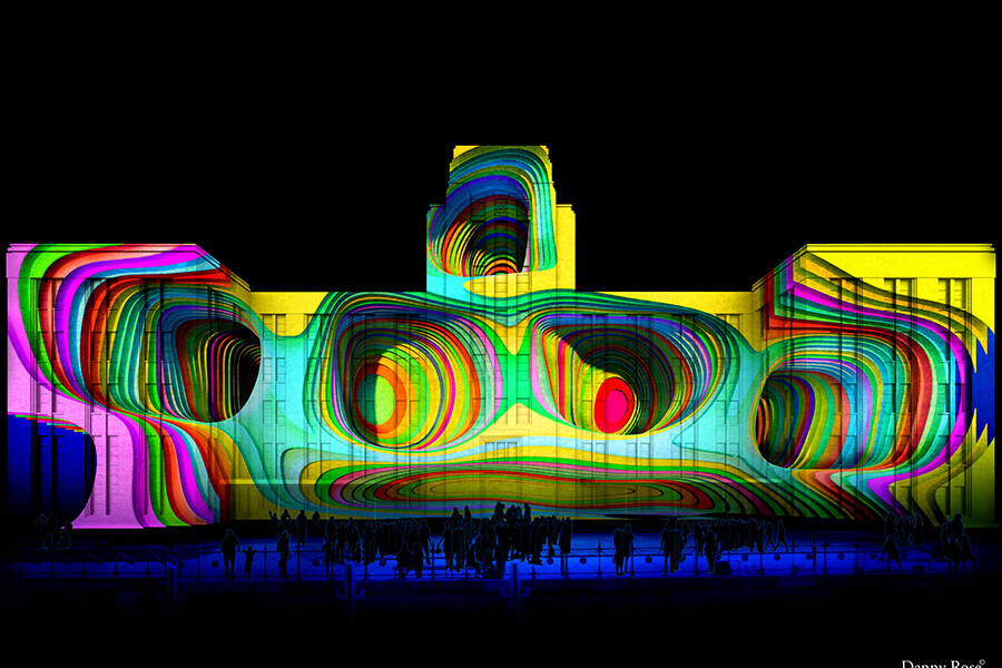 A brightly lit building features colorful, swirling patterns projected onto its facade, with a crowd gathered in front.