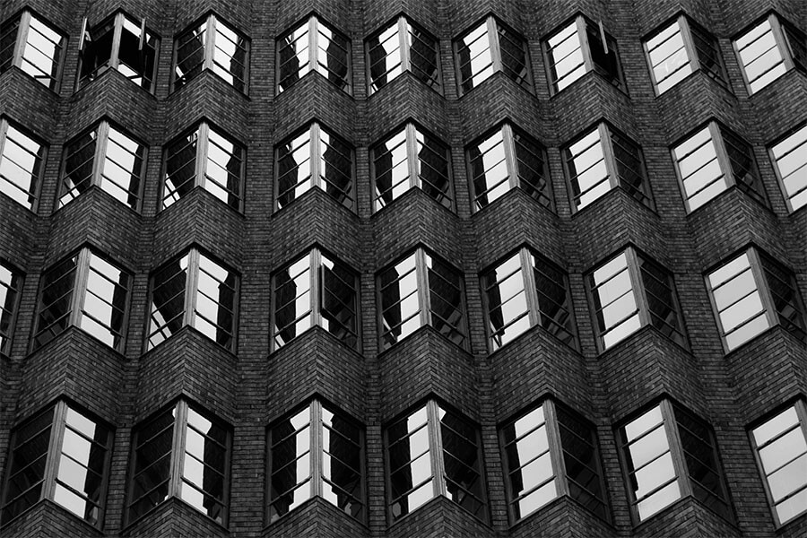 A close-up view of a building's facade showcasing repeating patterns of brick and rectangular windows in black and white.